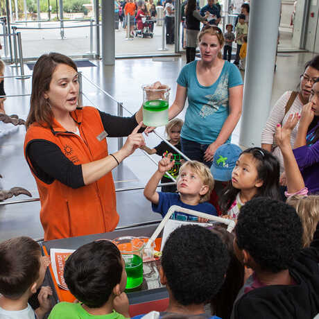 Students gathered around a docent giving a demonstration on ocean acidification