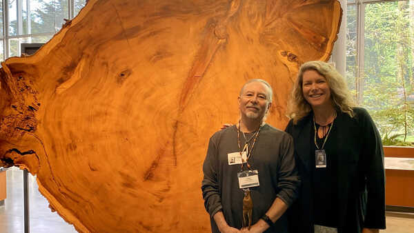 Gregg Castro and Shannon Tushingham pose in front of a redwood round in the Giants of Land and Sea exhibition in Cal Academy. 
