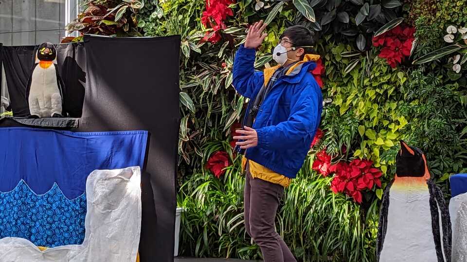 presenter on stage with 2 penguin puppets