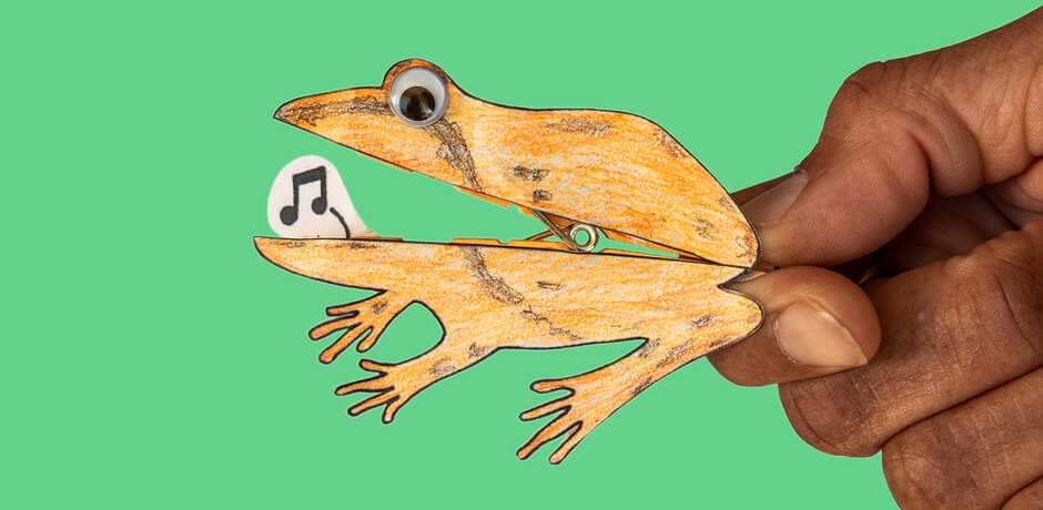 Handmade paper frog craft against green background