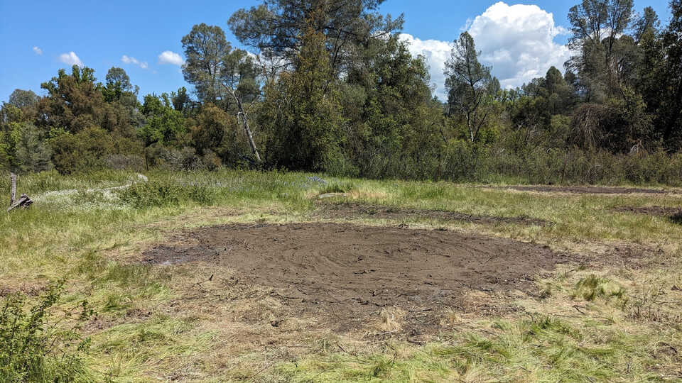 a wide shot shows a raked over patch of brown dirt, demonstrating how ash is incorporated into the ground. 