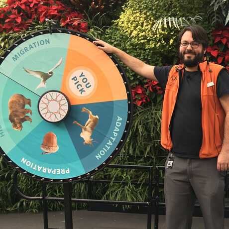 Presenter next to large game wheel and map of the arctic and antarctic 